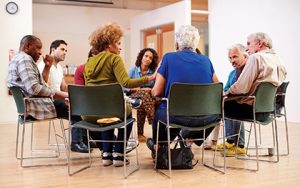 adults sitting in chairs in a circle talking